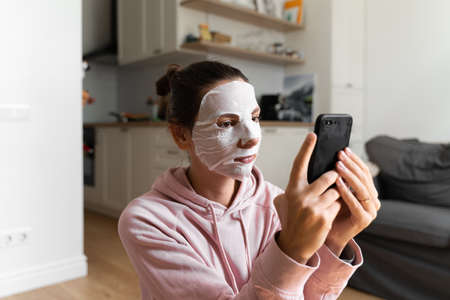 Young woman with beauty mask at home. Snackable wellness concept. Relaxation at home for young mother. Quick face mask for home spa.の写真素材