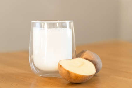 Potato milk photo on wooden background. Glass of alternative milk. Plant based vegetarian beverage. Lactose free drinkの写真素材
