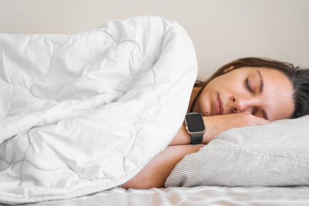 Young woman goes to sleep Phone addiction, insomnia. try to fall asleep. Sleep tracking on the phone and smart watch. Circadian rhythm.の写真素材