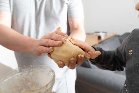 Close up view of the caucasian father helping to his child daughter adding and mixing ingredients in...