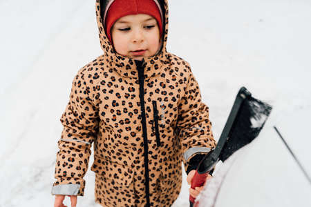Child cleaning car from the snow. Winter day family weekendの写真素材