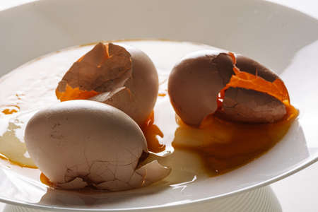 Cracked eggs on white plate with morning light. Brocken eggshell
