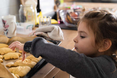 Caucasian pretty child girl cooking Christmas cookies at home kitchen, preschooler activity