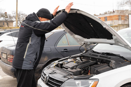 Close up view of the senior man inspecting car oil level while standing in front of the opened hood and looking inside. Stock photoの写真素材
