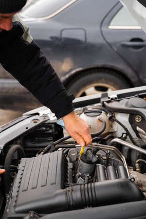 Close up view of the senior man inspecting car oil level while standing in front of the opened hood and looking inside. Stock photoの写真素材