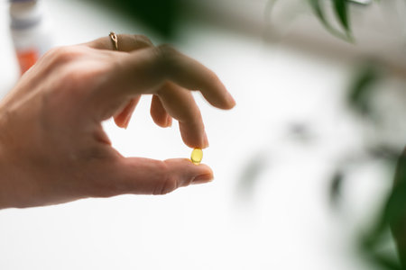 Close up of hand full of yellow softballs. Taking supplements, vitamin D or omega. Wellbeing biohacking conceptの写真素材