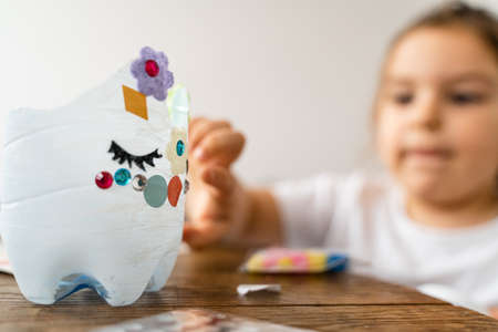 Caucasian preschool girl doing crafts with plastic bottle and paints. Recycle upcycling waste. Sustainable lifestyleの写真素材