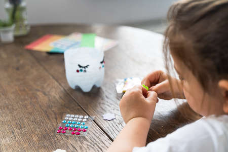 Caucasian preschool girl doing crafts with plastic bottle and paints. Recycle upcycling waste. Sustainable lifestyleの写真素材