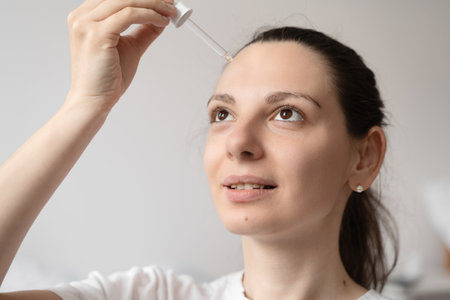 Close up of white woman hand applying oil of essential oil or serum for skin. Self care conceptの写真素材