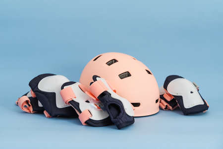 Top view of roller skates protective gear set - knee, elbow and wrist pads and helmet in pink colors. Blue background flat layの写真素材