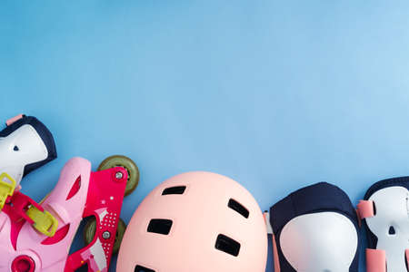 Top view of roller skates protective gear set - knee, elbow and wrist pads and helmet in pink colors. Blue background flat layの写真素材