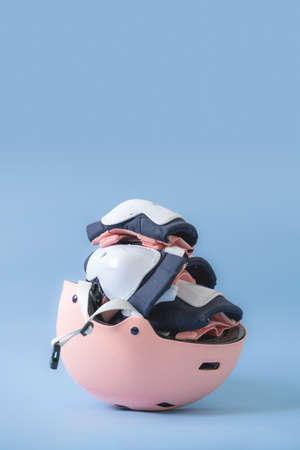 Top view of roller skates protective gear set - knee, elbow and wrist pads and helmet in pink colors. Blue background flat layの写真素材