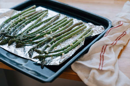 Green Asparagus sprouts on frying pen in kitchen. Grilled fresh vegetables