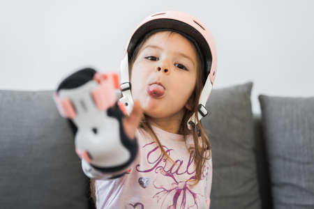 Preschool girl portrait with safety for outdoors activities. Pink helmet and wrist pads