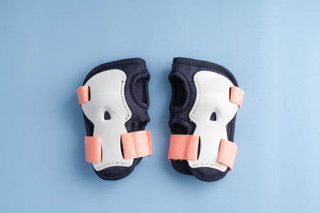 Top view of roller skates protective gear set - wrist pads in pink colors. Blue background flat layの写真素材