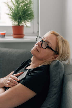 Middle age mature woman sleeping with book on the couch, home daydreamingの写真素材