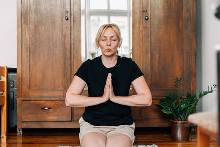 Middle age woman mediating and doing yoga at home. Mental health breathing exercise