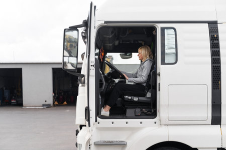 Caucasian mid age woman driving truck. trucker female worker, transport industry occupationの写真素材