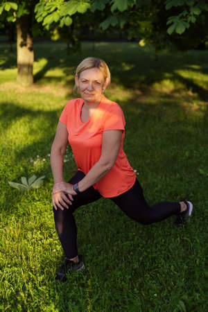 Mature woman doing sports outdoors on a sunny summer day in park