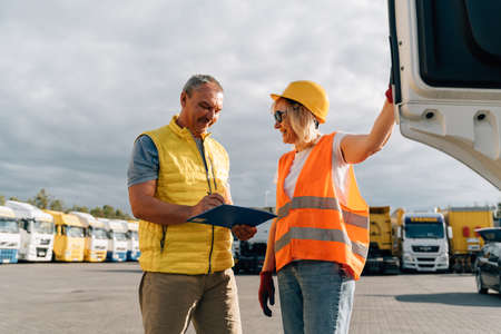 Mature woman and man at cargo warehouse, truck drivers delivery inspection