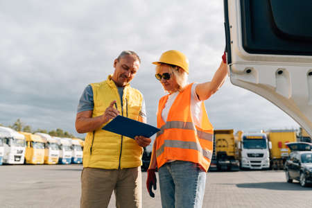 Mature woman and man at cargo warehouse, truck drivers delivery inspectionの写真素材
