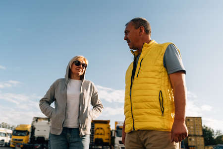 Mature woman and man at cargo warehouse, truck drivers delivery partners.