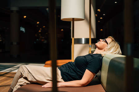 Mature blonde woman relaxing under sun light outdoors on a terrace