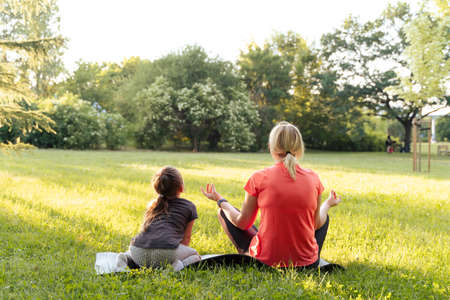 Middle age woman mother with child meditate together in parkの写真素材