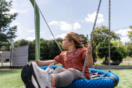 Preschooler caucasian girl swinging on rope net swing on playgroundの写真素材