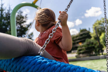 Preschooler caucasian girl swinging on rope net swing on playgroundの写真素材