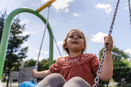 Preschooler caucasian girl swinging on rope net swing on playgroundの写真素材
