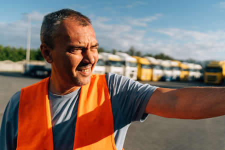 Portrait of caucasian mature man on semi-truck vehicles parking background. Truck driver worker