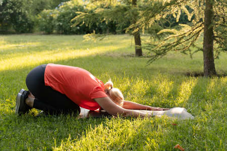 Mature woman doing sports outdoors on a sunny summer day in park