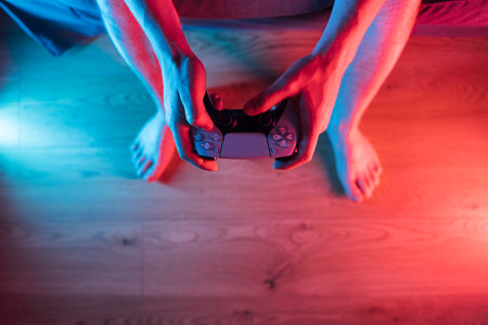 Man hands with game controller in neon light, top view