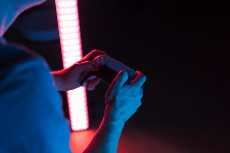 Man hands with game controller in neon light, top view