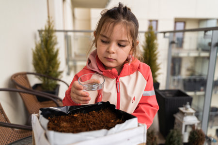 preschool age child girl seeding plants on the balcony. Urban gardening, sustainable educationの写真素材