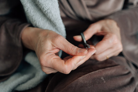 mature woman hands close-up using nail scissors for manicure at homeの写真素材