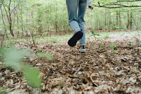 Low view wide angle of woman legs in jeans walking forest. hiking concept