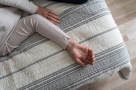 Mature woman curled lying on the bed at home top view. Depression, mental health, abuse problemの写真素材