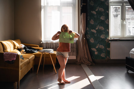 5 years old girl dancing with painting in the room in sunlightの写真素材