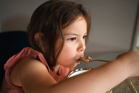 Child girl eating with spoon from the bowl at home.の写真素材