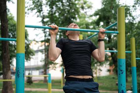 Middle age man doing pull-ups on the outdoors workout area