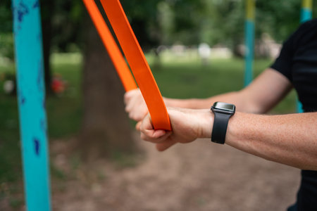 Middle age man doing strength exercises with resistance bands outdoors in parkの写真素材