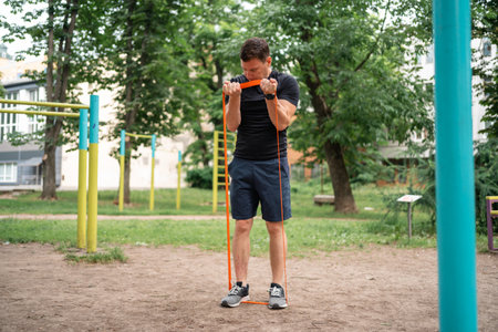 Middle age man doing strength exercises with resistance bands outdoors in park