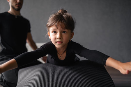 Young 5 years old girl doing gymnastics with the coach. Healthy active kids development, sport trainingの写真素材