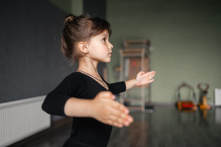 Child girl standing in black sport bodysuit in dancing studio during training posture. 4 5 years old preschool age. Healthy physical developmentの写真素材