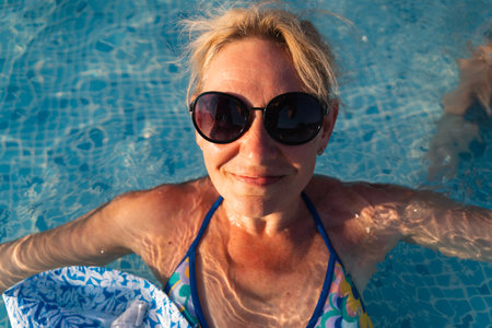 Mature woman in poolside, summer hot weather relax. Holidays in the pool. Swimming activity for healthy lifestyleの写真素材