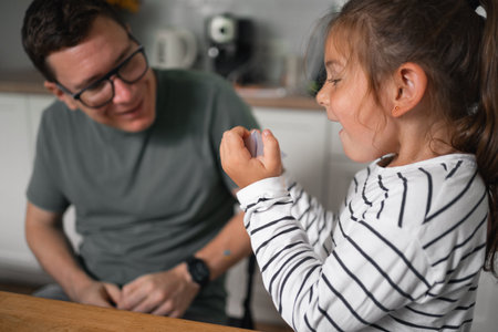 Father and child girl doing origami crafts together. Modern parenthood, weekend education activities at home of parents with children.の写真素材