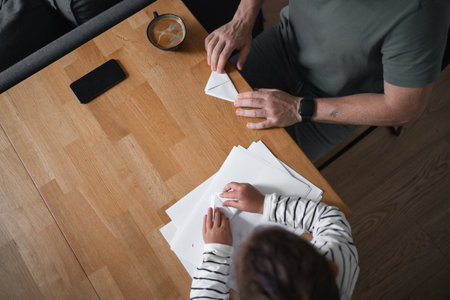 Father and child girl doing origami crafts together. Modern parenthood, weekend education activities at home of parents with children.の写真素材