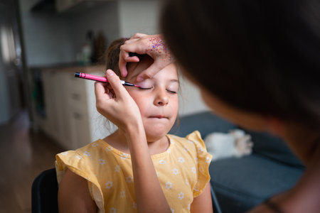 Close-up of makeup artist doing kids makeup with pink eyeliner. Small girl party or birthday day preparation.の写真素材